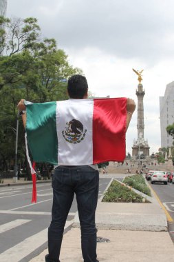 Mexico City, Meksika - 23 Ağustos 2023 İnsanoğlu ulusal bayramları kutlamak için Bağımsızlık Meleği 'nin önünde gururla Meksika bayrağını kaldırır.
