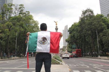 Mexico City, Meksika - 23 Ağustos 2023 İnsanoğlu ulusal bayramları kutlamak için Bağımsızlık Meleği 'nin önünde gururla Meksika bayrağını kaldırır.