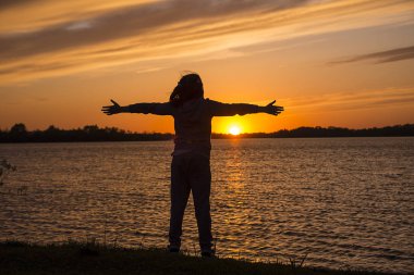Kırmızı günbatımı, gölgesinde bir çocuk elleri güneşe yayılıyor