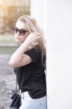 Akşam güneşin uzun, kıvırcık saçlı güneş gözlüklü bir kız portresi,