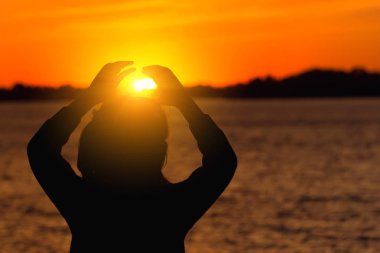 akşam güneşi karşı kızı silüeti, kırmızı günbatımı kalp eller güneşe doğru yapar
