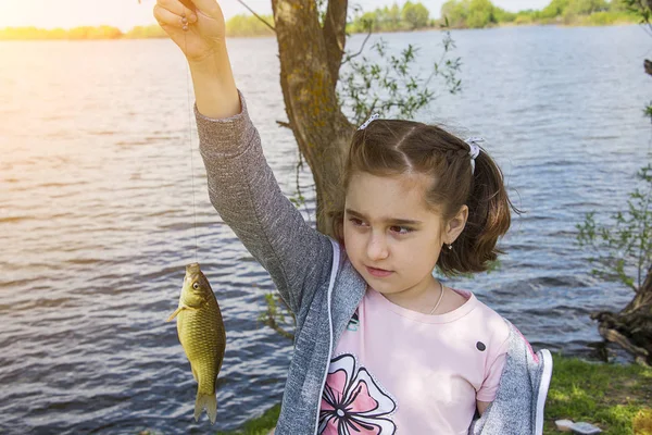 girl holding a fish caught in her hand ,rejoicing and smiling