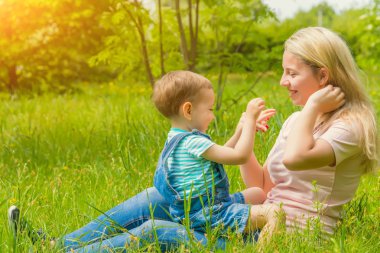 Anne ve çocuk da güneşli havalarda mutlu aile yeşil çimenlerin üzerinde dinlenme Park, doğada