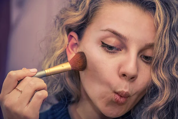 girl brush makes makeup on the face powder applied to the cheeks