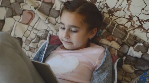 Девушка Играет Игру Планшете Рядом Экраном Лежит Диване — стоковое видео