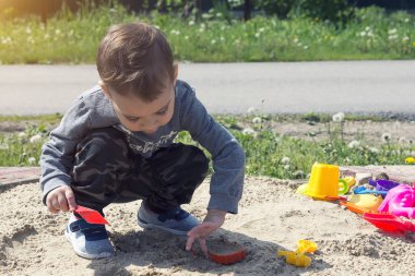 güneşli havalarda parkta oyun oynayan çocuk kumda oynarken küçük çocuk