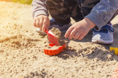 Eller çocuğun kum çocuk kum kırmızı bir spatula ile çalış