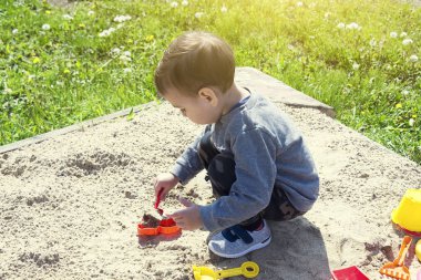 güneşli havalarda parkta oyun oynayan çocuk kumda oynarken küçük çocuk