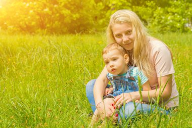 Anne ve çocuk da güneşli havalarda mutlu aile yeşil çimenlerin üzerinde dinlenme Park, doğada