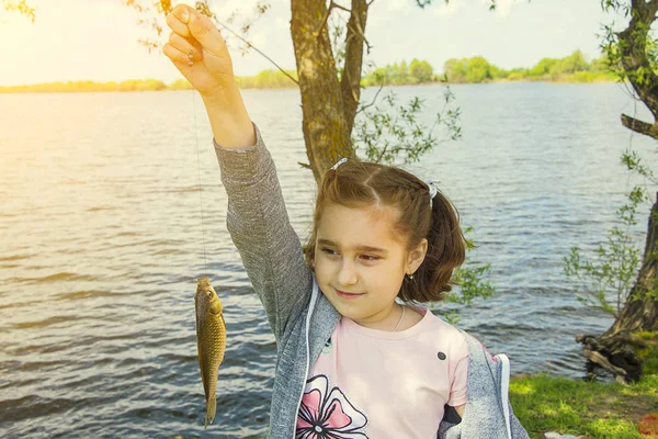 喜びと笑顔にお魚くわえた女の子が彼女の手でキャッチ — ストック写真