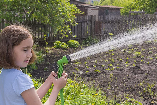 Menina Uma Camiseta Azul Regando Jardim Com Água Uma Mangueira — Fotografia de Stock