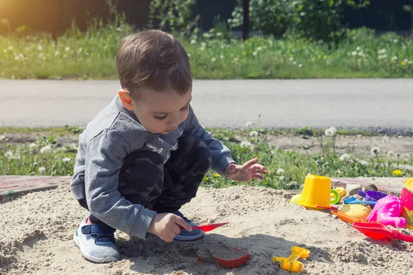 little boy playing in the sand, the child in sunny weather playing in the park on the playground