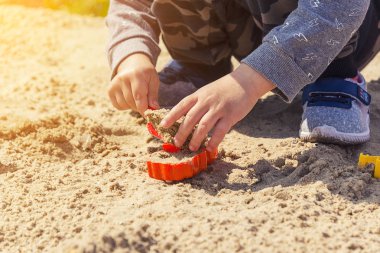 Eller çocuğun kum çocuk kum kırmızı bir spatula ile çalış