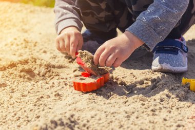 Eller çocuğun kum çocuk kum kırmızı bir spatula ile çalış