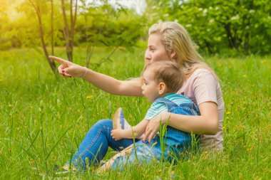 Anne ve çocuk da güneşli havalarda mutlu aile yeşil çimenlerin üzerinde dinlenme Park, doğada