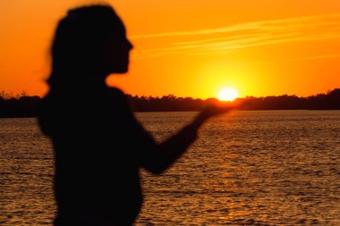 akşam arka plan üzerinde bir kız silüeti güneş kırmızı günbatımı, tutar elini güneşte