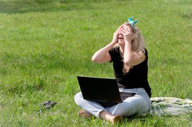 duygusal bir sosyal ağ yazma çimenlerin üzerinde oturan bir dizüstü bilgisayar ile kız