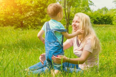 Anne ve çocuk da güneşli havalarda mutlu aile yeşil çimenlerin üzerinde dinlenme Park, doğada