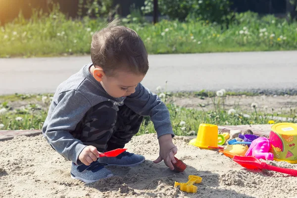 little boy playing in the sand, the child in sunny weather playing in the park on the playground