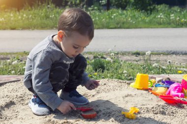 güneşli havalarda parkta oyun oynayan çocuk kumda oynarken küçük çocuk