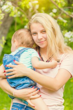 Anne ve çocuk da güneşli havalarda mutlu aile yeşil çimenlerin üzerinde dinlenme Park, doğada
