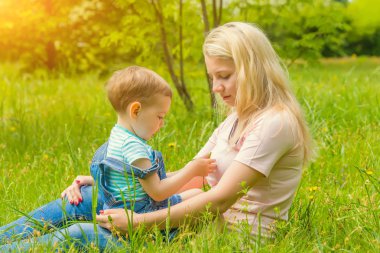 Anne ve çocuk da güneşli havalarda mutlu aile yeşil çimenlerin üzerinde dinlenme Park, doğada