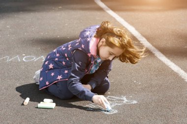rüzgarlı hava, küçük bir kız farklı yazıtlar yazıyor çocuk asfalt, tebeşir ile boyar