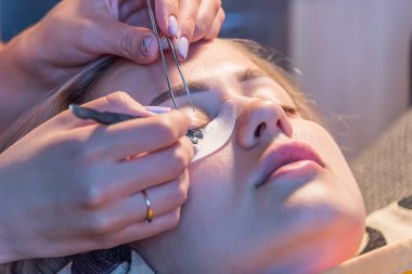 Kız evde sıcak ışık ile kirpik tutkallar