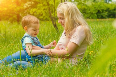 Anne ve çocuk da güneşli havalarda mutlu aile yeşil çimenlerin üzerinde dinlenme Park, doğada