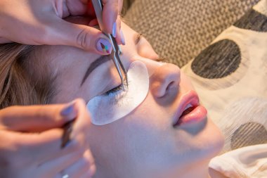 Kız evde sıcak ışık ile kirpik tutkallar