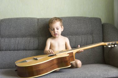 kanepede oturan gitar oynayan çocuk