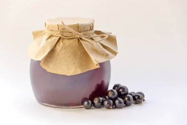 beyaz zemin üzerinde bir reçel kavanoz yanındaki siyah frenk üzümü