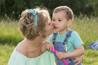Anne ve oğlu lolipop ve sabun köpüğü ile yaz parkında