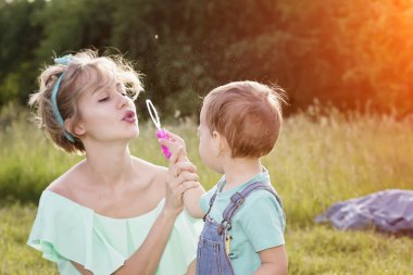 Anne ve oğlu lolipop ve sabun köpüğü ile yaz parkında