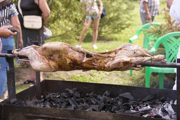 mutton is cooked on a spit on an open fire. street food