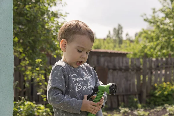 Ett Barn Trädgården Vattna Blommor Liten Pojke Med Vattenslang Som — Stockfoto