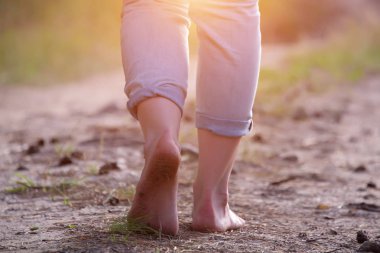 orman yolu boyunca kum üzerinde yürüyen kadın ayakları