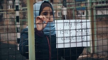 mülteci kız beyaz bir levha üzerinde yazıt ile 