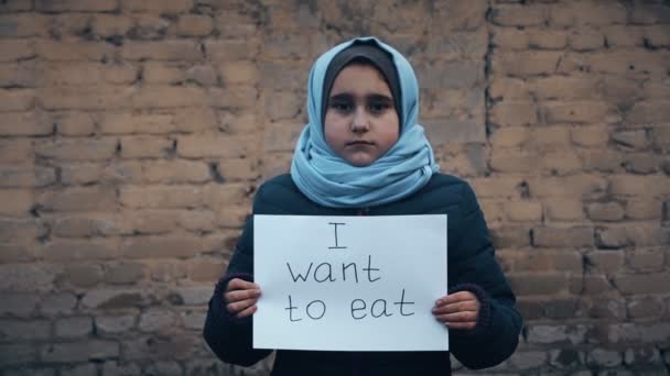 难民女孩与白色的床单上的题字 我想吃 — 图库视频影像