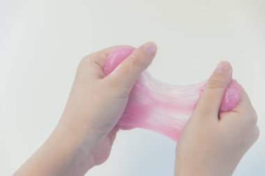 pembe çamur elinde, kırmızı yapışkan hamuru çekerek