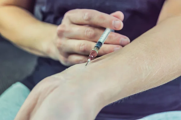 Joven adicta con una jeringa en la mano — Foto de Stock