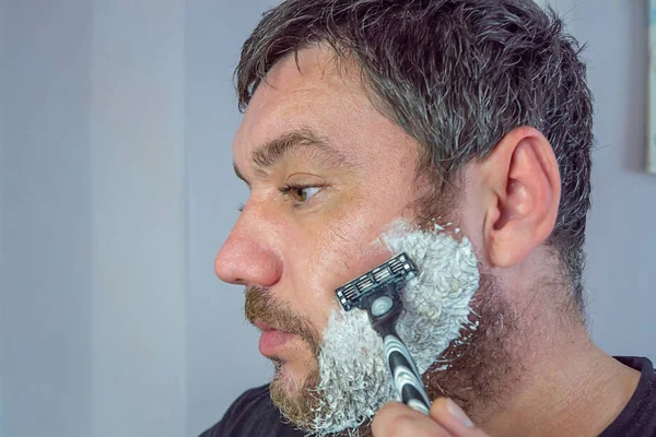 Чоловік з сірою бородою голиться — стокове фото