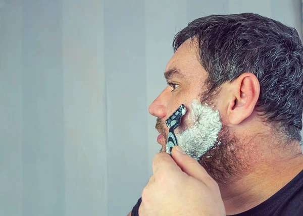 A man with a gray beard shaves — Stock Photo, Image