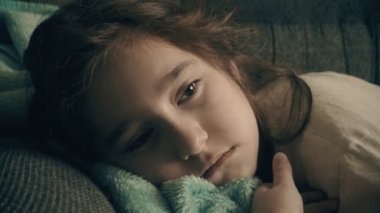 Bebek kız bir yastık üzerinde yatıyor. Kırmızı saçlı kız uykuda düşüyor. Çocuk yatmadan önce yanıp söner