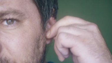 Orta yaşlı adam kulak yakın çekim temizler. kulaklar için bir değnek ile kulak fırçası. Eski bir beyaz adamın büyük kulağı bir kulak çubuğu ile temizlenir..