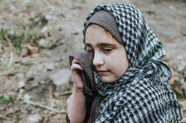 savaşta bir mülteci çocuk, harabeler üzerinde kirli bir yüzü olan Müslüman bir kız, barış ve savaş kavramı, çocuk ağlıyor ve yardım bekliyor.