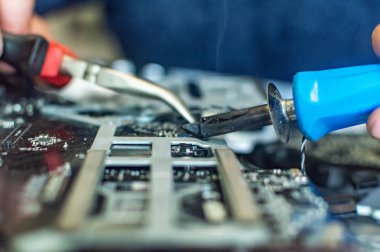 Bir adam bilgisayarı tamir eder, lehimler, elektronik ve modern teknolojileri tamir eder.