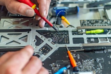Bir adam bilgisayarı tamir eder, lehimler, elektronik ve modern teknolojileri tamir eder.