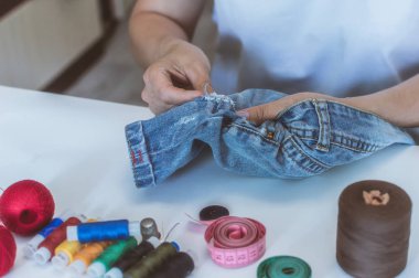 kadın elleri, bir terzi iplik makaraları yalan bir masada elbise diker