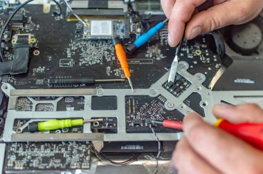 Bir adam bilgisayarı tamir eder, lehimler, elektronik ve modern teknolojileri tamir eder.